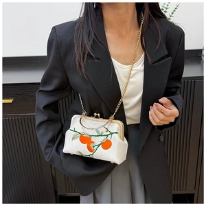 Détail du sac blanc avec broderie de fruits orange et accessoires en métal doré chic