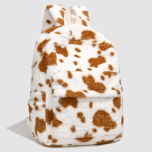 Detail of soft plush backpack featuring brown cow pattern and front zipper pocket