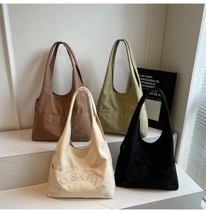 Détail de quatre sacs fourre-tout en toile marron, vert, crème et noir avec lettres gaufrées