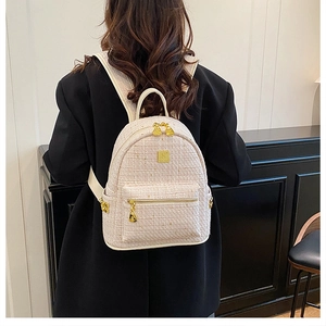 Zaino chic in tweed beige con dettagli dorati indossato da una modella in giacca