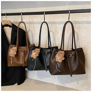 Detailed view of large tote bags in brown and black with cute bear charms for women