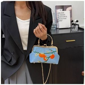 Détail du sac bleu ciel avec broderie de persimmon et poignée en perles dorées