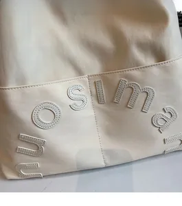Gros plan d'un sac cabas beige avec lettrage NUOSIMA brodé en 3D de haute qualité