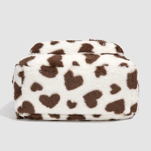 Close-up of white plush backpack featuring brown heart patterns and soft faux fur texture