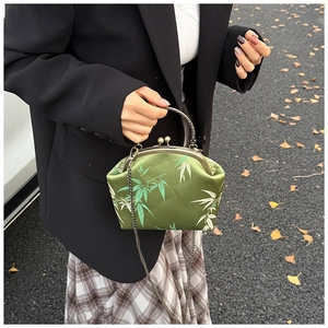 Close-up of green silk shell bag with bamboo leaves on autumn leaves background