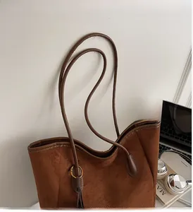 Sac cabas en daim marron avec franges présenté avec des accessoires de bureau chic