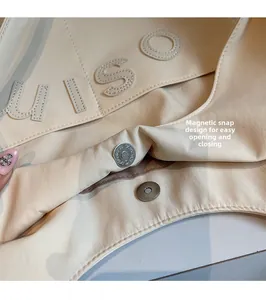 Gros plan sur le fermoir magnétique du sac cabas en toile beige avec broderie LUISO