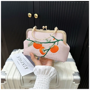 Détail du sac en soie rose avec broderie exquise de kaki orange et de feuilles