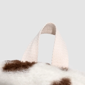 Detailed macro view of plush cow print backpack with sturdy beige woven handle