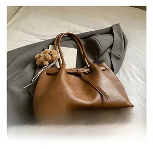Close-up of vintage brown tote bag with leather texture and cute plush bear charm