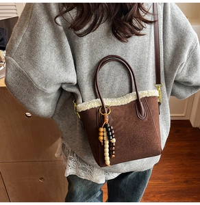Détail du sac bandoulière en daim marron avec bordure en similicuir et charme perlé