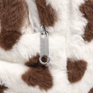 Detailed macro view of the silver metal zipper and soft cow print faux fur texture