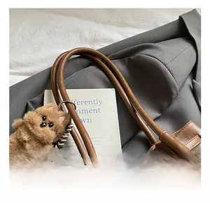 Close-up of retro brown leather tote handles with metal buckles and plush dog charm