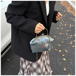 Detail of elegant retro blue-grey satin kiss-lock bag with bamboo pattern and metal chain