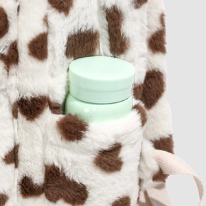 Close-up of side pocket on fuzzy cow print backpack holding a green water bottle