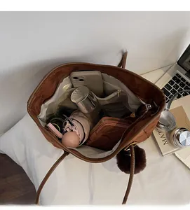 Intérieur spacieux d'un sac cabas en daim marron avec objets du quotidien et breloque