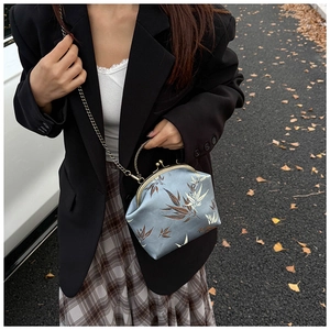Close-up of vintage blue silk handbag with bamboo pattern and antique metal chain strap
