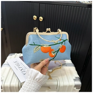 Détail du sac coquille en soie bleu clair avec broderie et bandoulière chaîne dorée