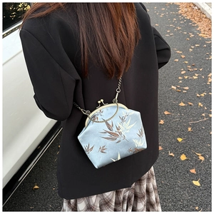 Chic light blue chain shell bag with bamboo patterns worn by a model in outdoor setting