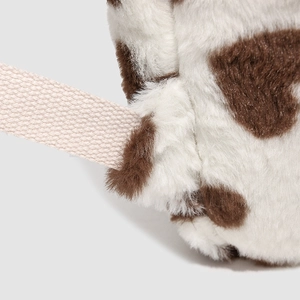 Detail of plush cow print backpack featuring woven pink and beige shoulder straps
