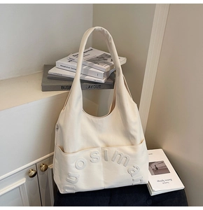 Détail du lettrage en relief sur le cabas en cuir beige avec large bandoulière