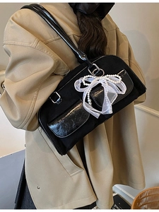 Retro black underarm bag with lace bows and pearl charms shown on a model