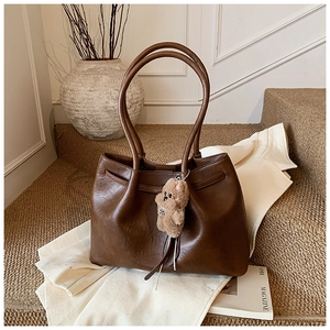 Detail of vintage brown leather tote bag with a cute plush teddy bear charm pendant