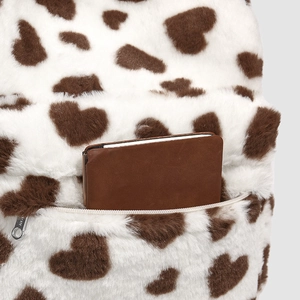 Detailed view of plush backpack front zipper pocket with brown heart pattern print