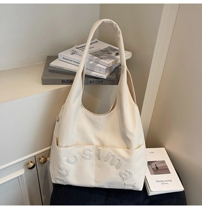 Gros plan d'un sac cabas en toile crème avec logo en relief et poche frontale