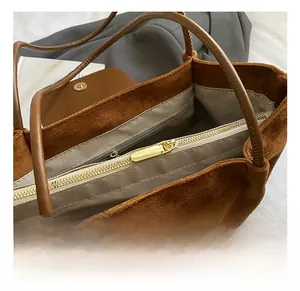 Close-up of brown suede tote bag with golden metal zipper and herringbone lining detail