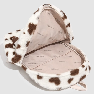 Detail view of the plush backpack featuring cow print and branded inner lining