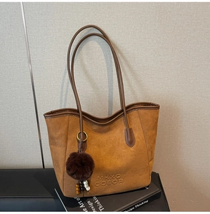Gros plan détaillé d'un sac cabas en daim marron avec logo et porte-clés pompon doux