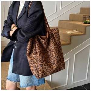 Detail of large leopard print tote bag in plush suede texture with a wide shoulder strap