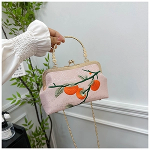 Détail du sac en satin rose avec broderie de persimmon et poignée en métal doré