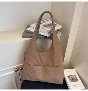Gros plan du sac cabas en toile marron avec logo en relief et poche avant pratique