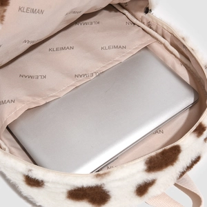 Detailed view of plush cow print backpack interior with a laptop in the large compartment