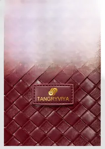 Dettaglio della trama in pelle intrecciata bordeaux con logo dorato su placca in metallo