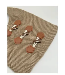 Detailed view of the khaki knitted fabric featuring stylish toggle horn buttons