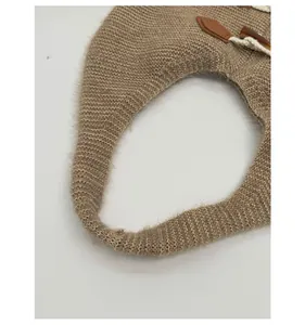 Detail of wide knitted shoulder strap with leather horn buckle on a large tote bag