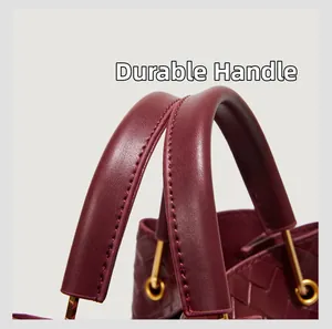 Dettaglio del manico della borsa a secchiello in pelle intrecciata bordeaux con fibbie oro