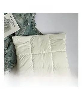 Detailed close-up of a quilted off-white laptop sleeve with artistic styling props