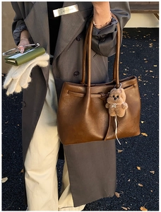 Close-up of a large brown tote bag with a cute plush puppy pendant charm accessory