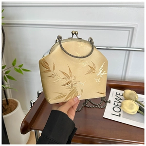 Detail of satin shell bag featuring bamboo embroidery and vintage metal chain strap