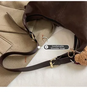 Detail view of adjustable strap with gold buckle on a brown leather half-moon shoulder bag