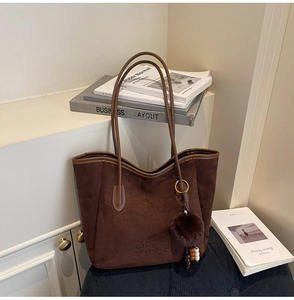 Détail du grand sac cabas en suédine marron foncé avec logo embossé et pendentif pompon