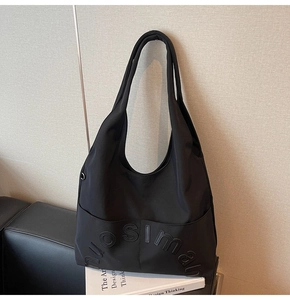 Vue détaillée du sac cabas en toile noire avec lettres en relief sur la poche extérieure