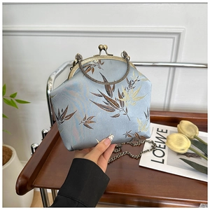 Detail of light blue silk embroidery handbag with antique metal frame and chain handle