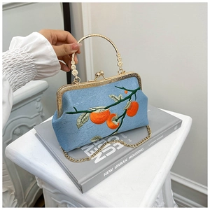 Détail d'un sac à main en satin bleu avec broderie et fermoir métallique doré élégant