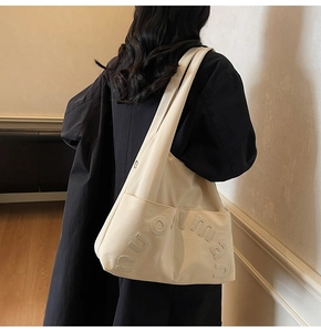 Détail du cabas en toile blanc cassé avec broderie de lettres 3D et poche latérale
