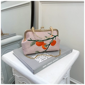 Détail du sac coquillage rose avec broderie de persimmon et garniture dorée